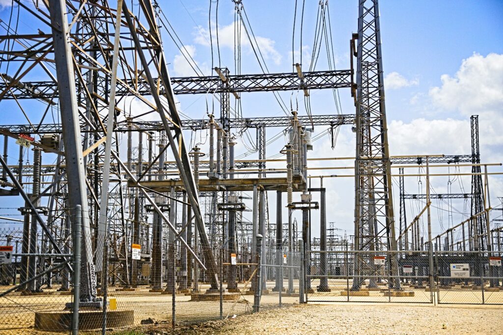 Hoogspanningsmasten en een transformatorstation in een Nederlands landschap