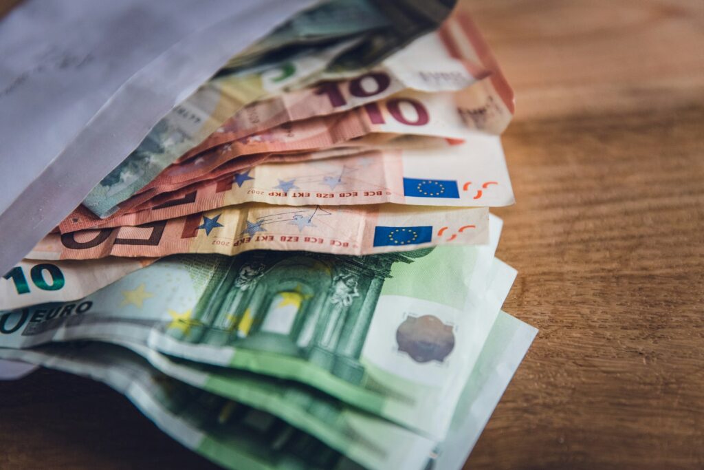 Kleine eurobiljetten en munten in een envelop op tafel