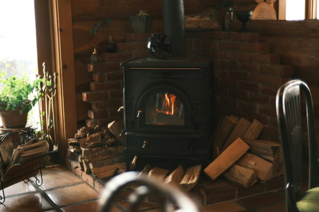 Brandende houtkachel in een woonkamer met een stapel brandhout ernaast
