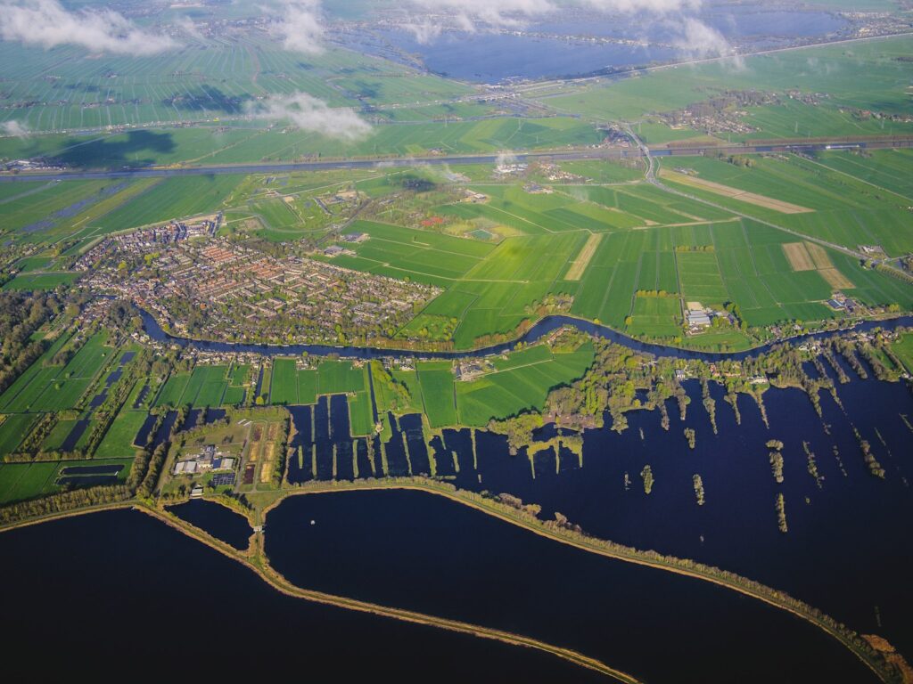 Dijk met hoog water in de rivier naast een rij huizen