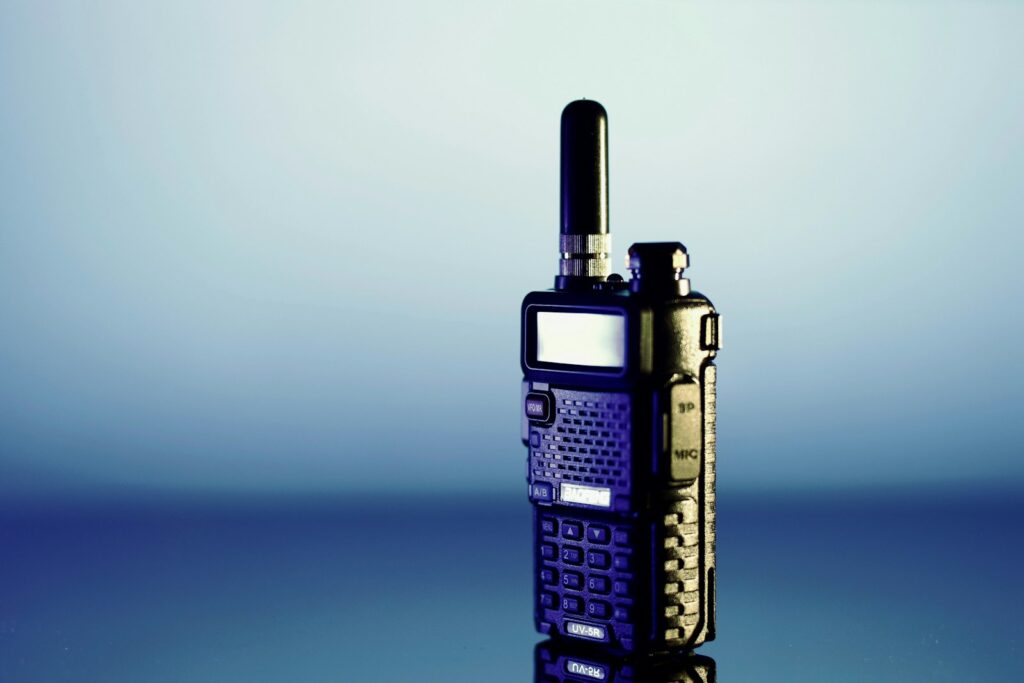 Twee walkietalkies op een houten tafel naast een zaklamp