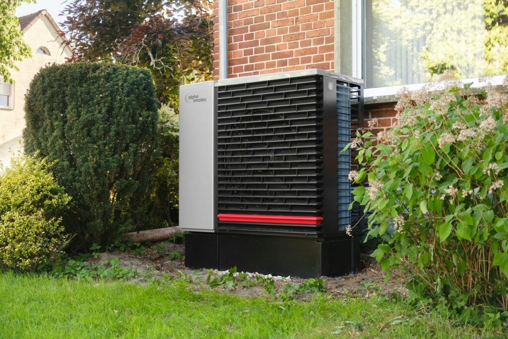 Buitenunit van een warmtepomp tegen de gevel van een woning