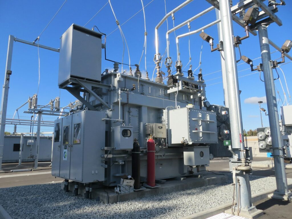 Hoogspanningsstation met transformatoren en masten onder een grijze lucht