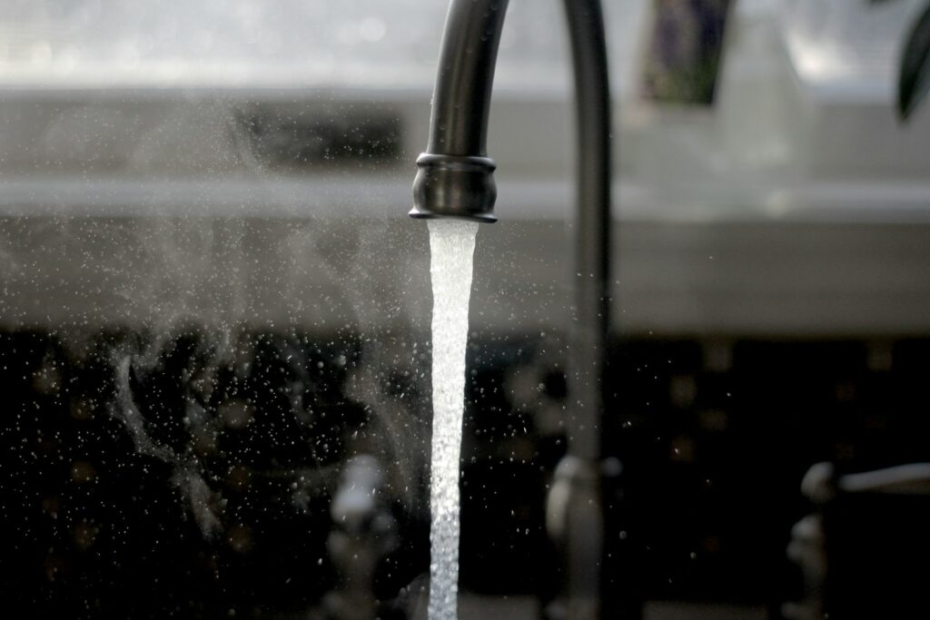 Glas water onder een lopende keukenkraan