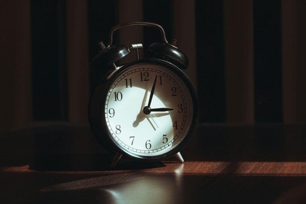 Wekker en telefoon op een nachtkastje in een donkere slaapkamer